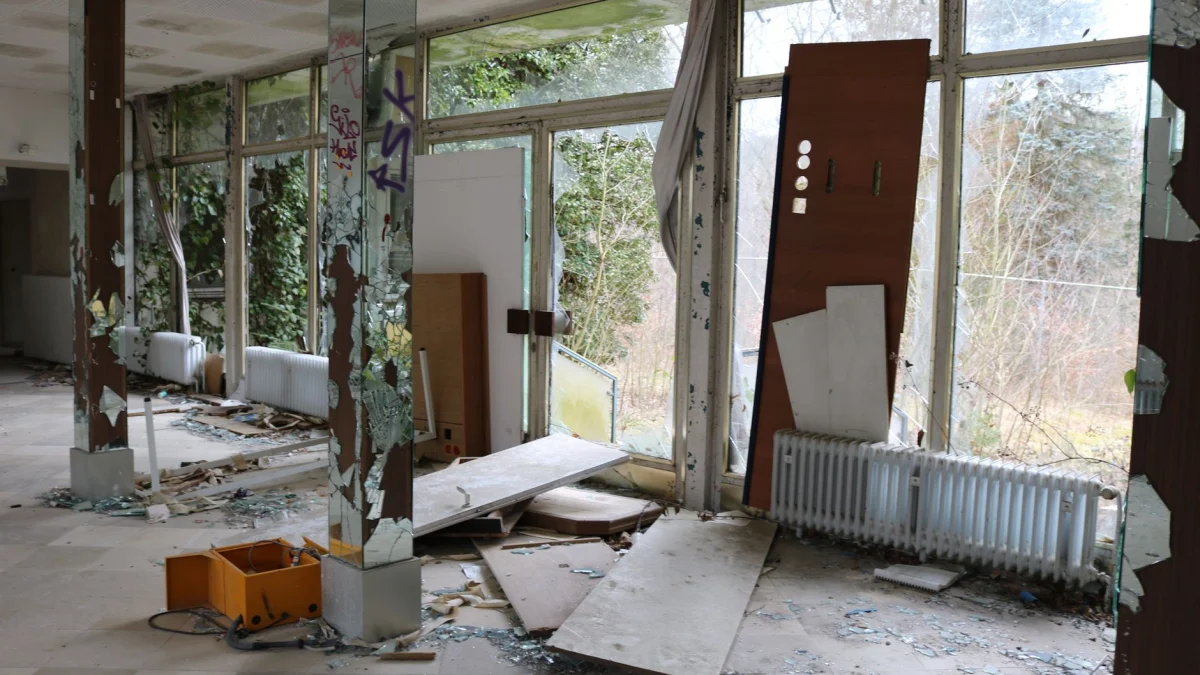 Interieurweergave van een verlaten gebouw met gebroken ramen en puin.