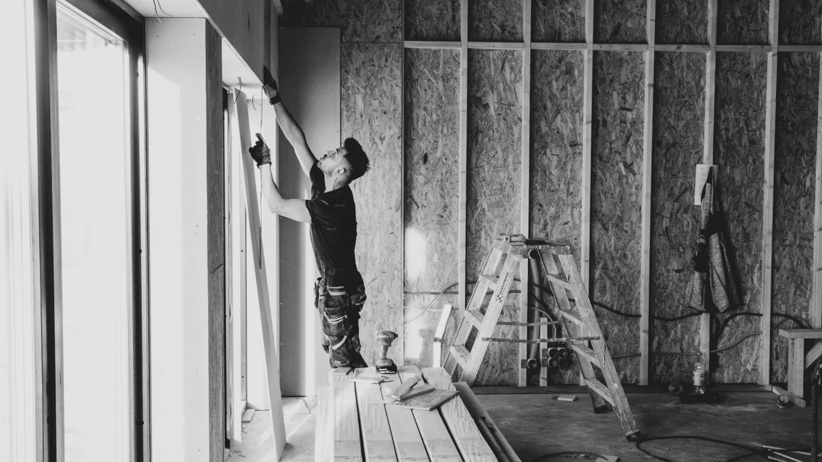 Zwart-witfoto van een werknemer die binnen drywalls installeert, Falun, Zweden.