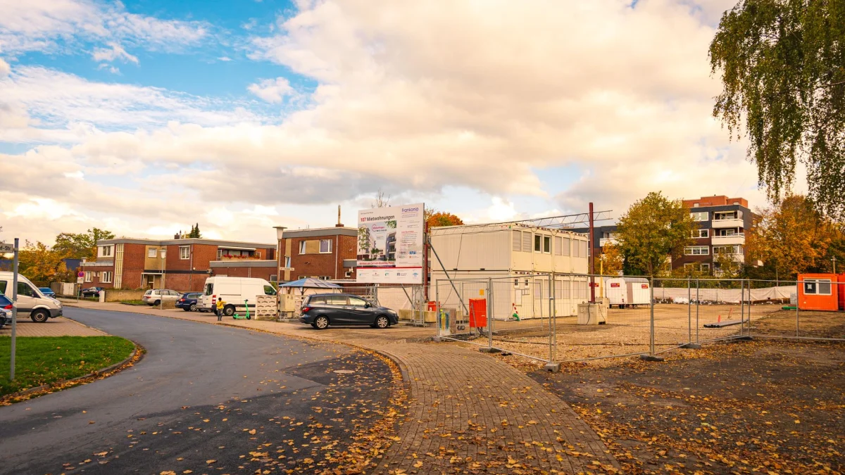 Stedelijke bouwplaats in de herfst met gevallen bladeren en woongebouwen eromheen.